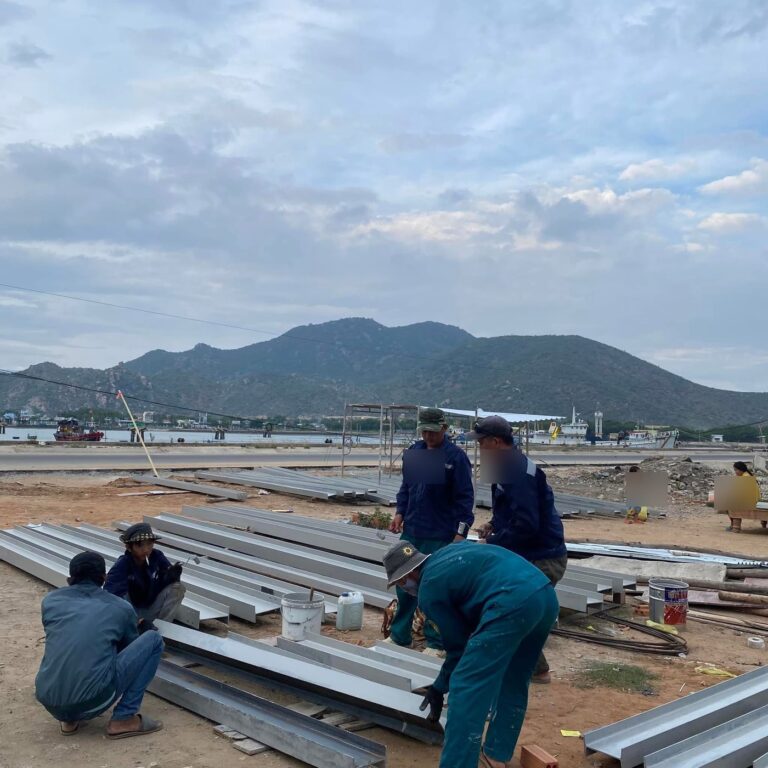 Tổ thợ SH Design gia công khung thép tại công trường ven biển, phía sau là núi và tàu cá
