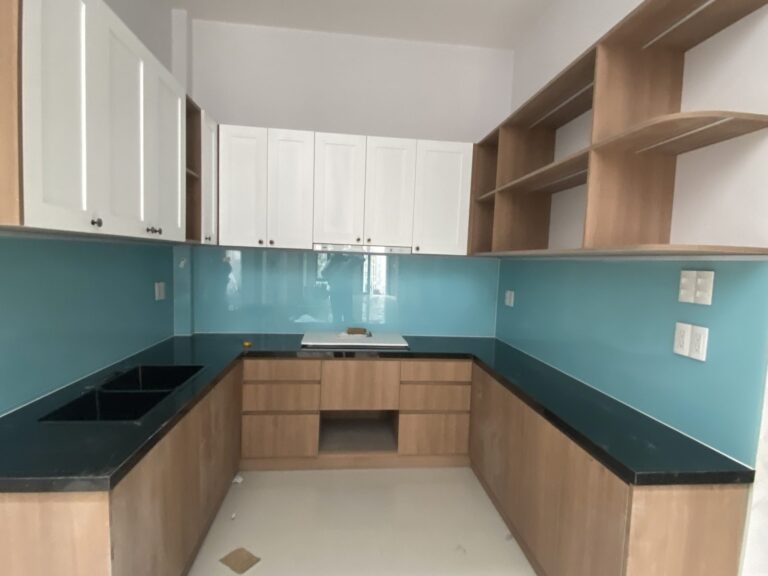 Bếp chữ U tủ gỗ, mặt đá đen, kính ốp tường màu xanh đã lắp xong