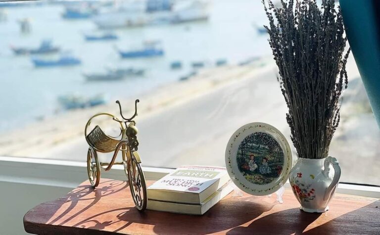 Bậu cửa sổ gỗ trang trí, phía sau là bãi biển và tàu cá