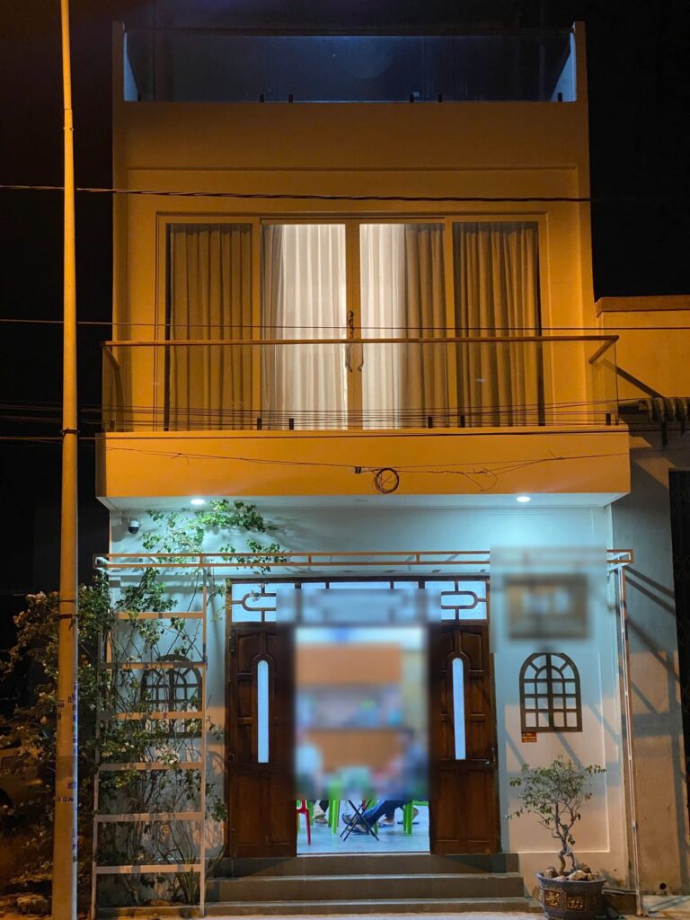 Mặt tiền nhà phố hai tầng lúc tối, ban công rèm và cửa gỗ vòm đã hoàn thiện