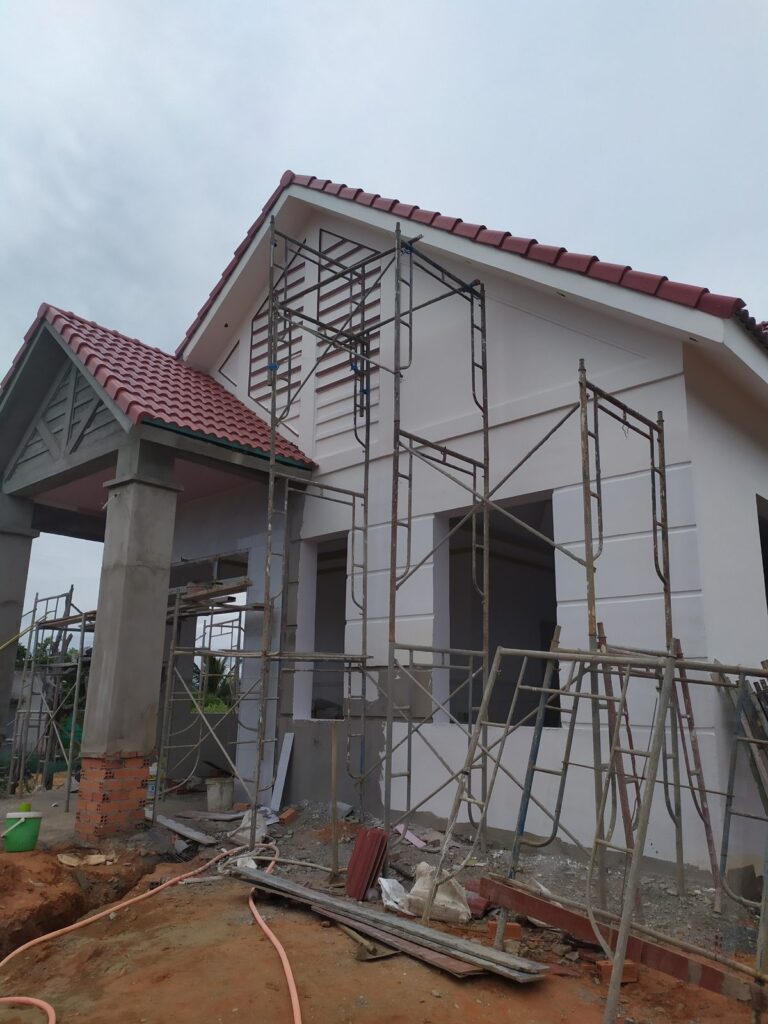 Nhà mái ngói đang sơn hoàn thiện mặt ngoài, giàn giáo còn dựng