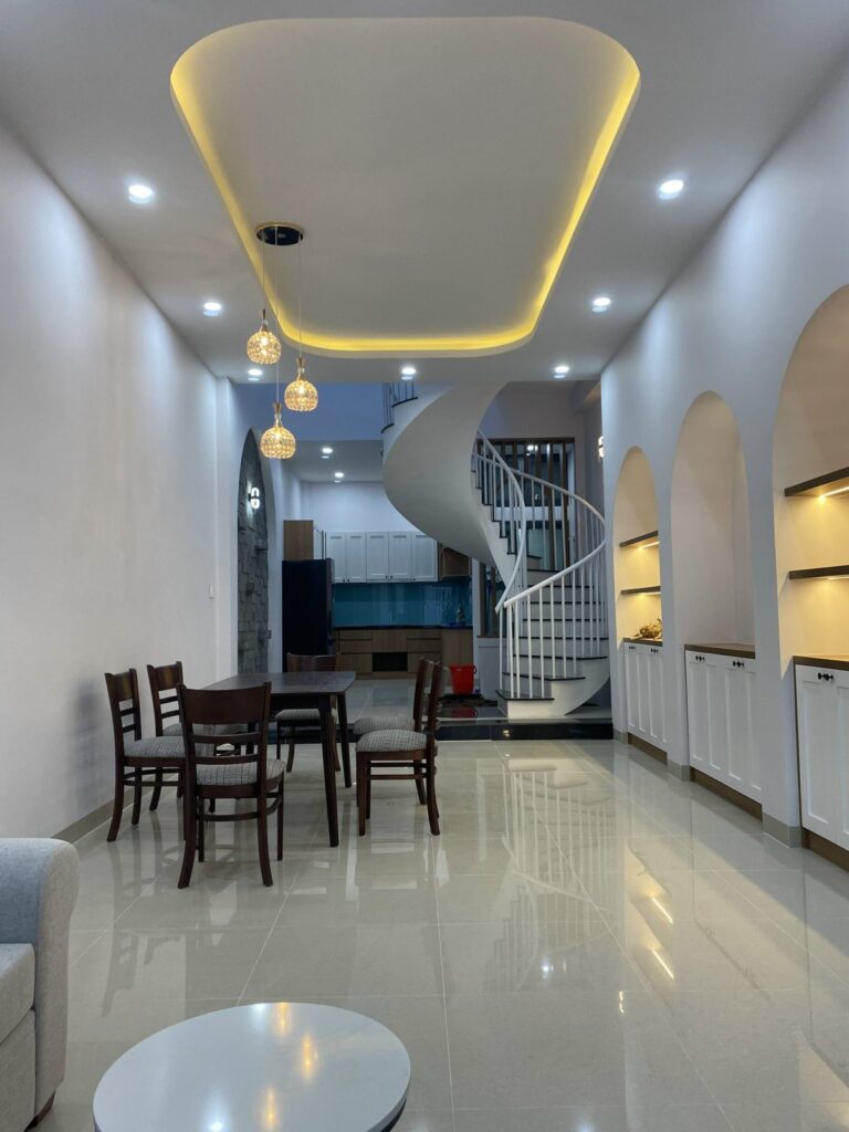 Phòng khách thông bếp, cầu thang xoắn trắng và hốc tường vòm sau khi bàn giao
